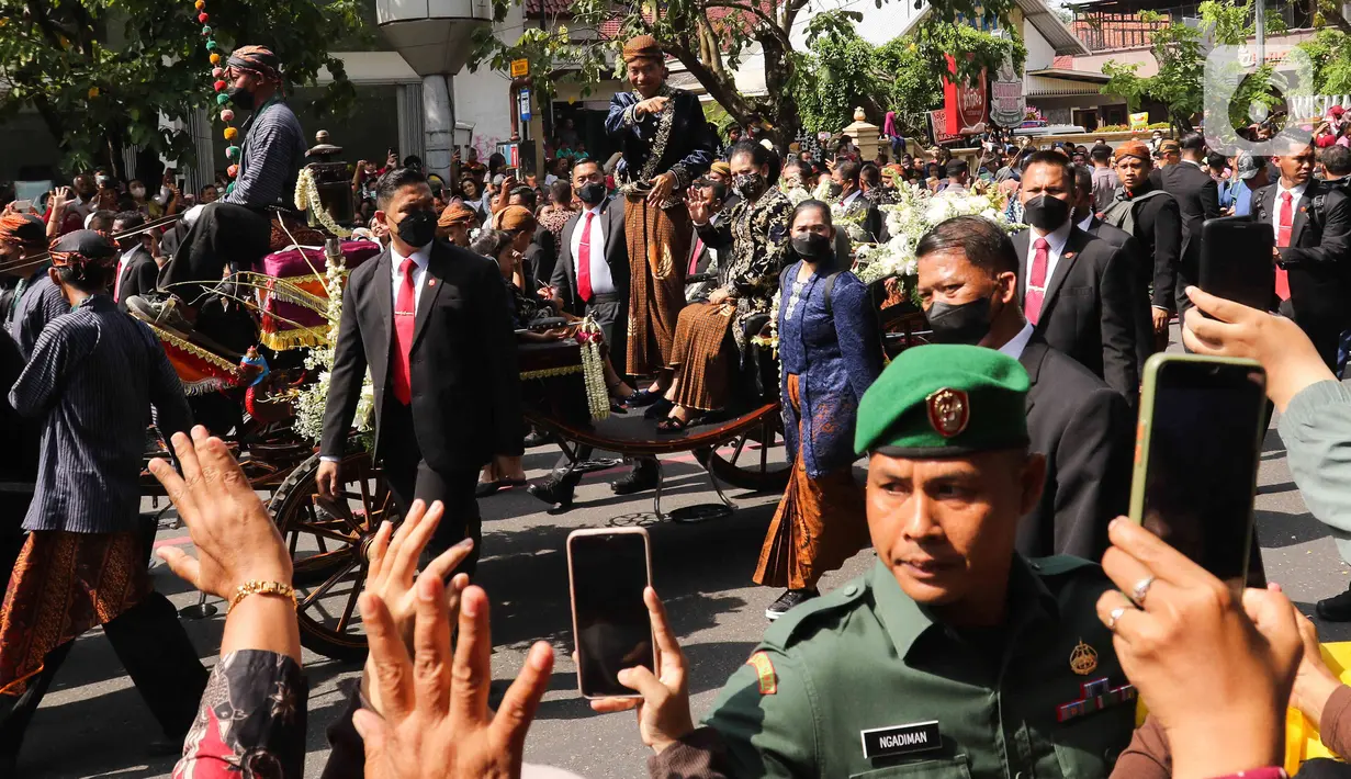 Presiden Joko Widodo menyapa warga saat menaiki kereta dalam mengikuti prosesi kirab Ngunduh Mantu di kawasan Selamet Riyadi, Solo, Jawa Tengah, Minggu (11/12/2022). Kirab ngunduh mantu pernikahan putra bungsu Presiden Joko Widodo, Kaesang Pangarep dan istrinya Erina Gudono yang dimulai dari Loji Gandrung menuju Pura Mangkunegaran tersebut disaksikan ribuan masyarakat Solo dan sekitarnya. (Liputan6.com/Herman Zakharia)