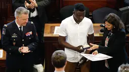 Imigran Mali Mamoudou Gassama menerima medali Grand Vermeil yang diberikan walikota Paris Anne Hidalgo (kanan) di Paris, Prancis (4/6). Mamoudou Gassama merupakan imigran gelap dari Mali yang tinggal di Prancis. (AFP/Francois Guillot)