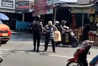 Ipda Suwinta saat membantu pria lansia penjual kerupuk pikul menyeberang jalan. (Liputan6.com/ Dok Ist)