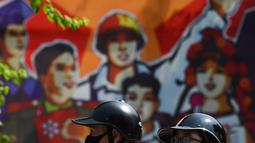 Warga mengendarai sepeda motor melewati spanduk yang menandai peringatan 75 tahun Hari Nasional Vietnam (1/9/2020). Peringatan 75 tahun Hari Nasional Vietnam jatuh pada tanggal 2 September 2020. (AFP Photo/Nhac Nguyen)