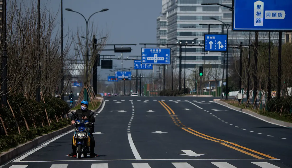 Pengendara sepeda motor terlihat di jalanan yang sepi dekat kantor pusat Alibaba di Kota Hangzhou, Provinsi Zhejiang, China, Rabu (5/2/2020). Pemerintah Hangzhou memberlakukan pembatasan pergerakan bagi warganya menyusul mewabahnya virus corona. (NOEL CELIS/AFP)