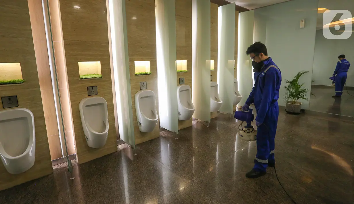 Petugas menyemprotkan cairan disinfektan di dalam toilet pria Lippo Mall Kemang, Jakarta, Senin (23/3/2020). Sejumlah titik yang menjadi sasaran penyemprotan adalah tempat yang sering disentuh publik seperti eskalator, area makan, pintu, mushola hingga lorong mall. (Liputan6.com/Fery Pradolo)