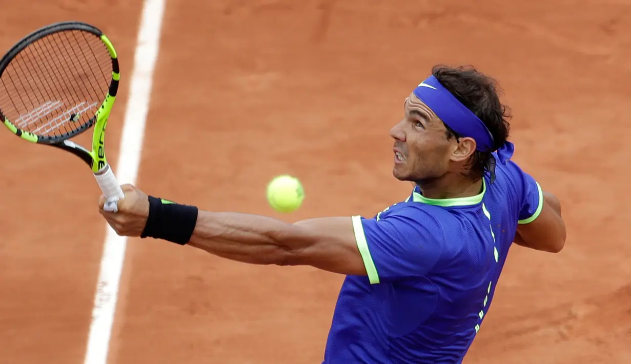 Petenis Spanyol, Rafael Nadal mengembalikan bola ke arah lawannya petenis Prancis, Benoit Paire pada babak pertama Prancis Terbuka  di Stade Roland Garros, Senin (29/5). Nadal mengalahkan tuan rumah dengan skor 6-1, 6-4, 6-1. (AP Photo/Petr David Josek)