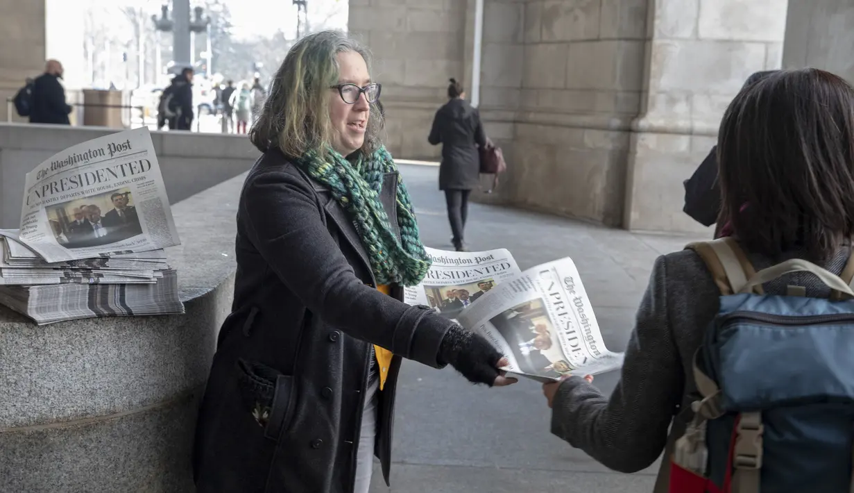 Aktivis membagikan surat kabar tiruan The Washington Post berisi Presiden Donald Trump mengundurkan diri di Washington, DC, Rabu (16/1). Koran dan berita palsu itu merupakan ulah iseng kelompok liberal bernama Yes Men. (Tasos Katopodis/Getty Images/AFP)