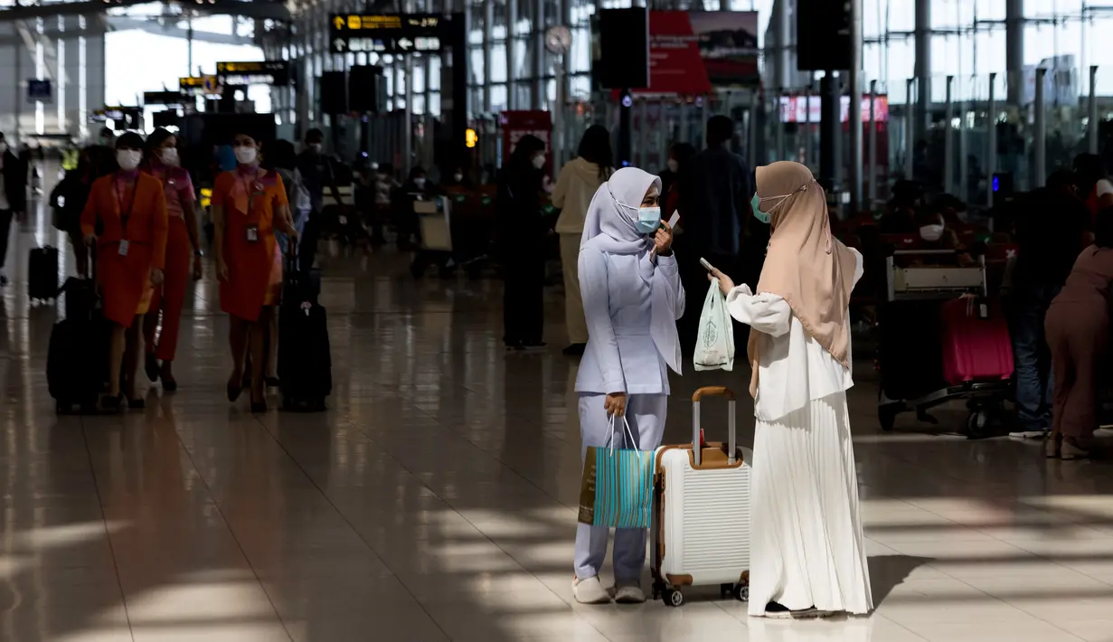 Penumpang menunggu dengan barang bawaan mereka di Bandara Suvarnabhumi di Bangkok, saat Thailand melanjutkan skema perjalanan bebas karantina untuk pelancong yang divaksinasi, Selasa (1/2/2022). Program ini sebelumnya ditangguhkan karena melonjaknya kasus Covid-19 di Thailand. (Jack TAYLOR/AFP)