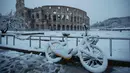 Sebuah sepeda tertutup salju tebal saat di parkir di depan Colosseum kuno di Roma, Italia (26/2). Hujan salju ini merupakan yang terlebat sejak 6 tahun terakhir. (AP Photo / Alessandra Tarantino)