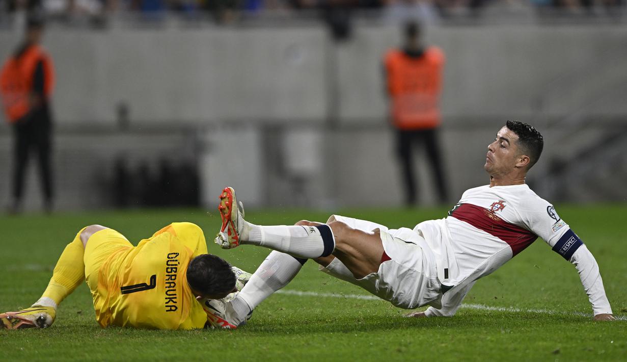 Pemain Portugal, Cristiano Ronaldo (kanan) berebut bola dengan kiper Slovakia, Martin Dubravka saat laga grup G Kualifikasi Euro 2024 di National Football Stadium in Bratislava, Slovakia, Sabtu (9/9/2023) dini hari WIB. Pertandingan tersebut diwarnai dengan insiden tekel horor Ronaldo ke kepala kiper Slovakia. (AP Photo/Radovan Stoklasa)