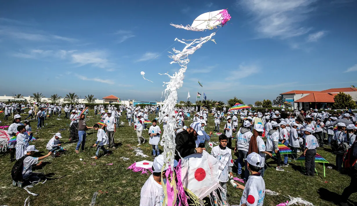 Anak-anak sekolah Palestina menerbangkan layangan dalam aksi solidaritas peringatan tujuh tahun gempa dan tsunami Jepang di Gaza, Selasa (13/3). Acara ini digagas oleh United Nations Relief and Works Agency (UNRWA). (SAID KHATIB/AFP)