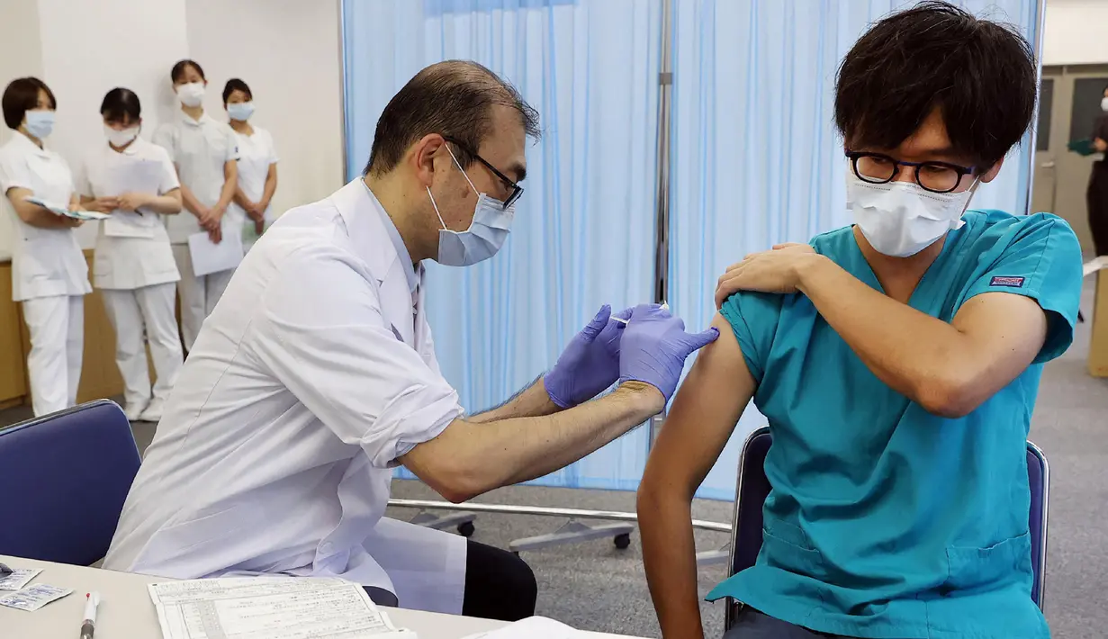 Seorang pria (kanan) menerima dosis ketiga vaksin COVID-19 Pfizer di Nagoya, prefektur Aichi, Rabu (1/12/2021). Jepang mulai memberikan suntikan booster COVID-19 kepada petugas medis di tengah kekhawatiran atas varian omicron yang telah terdeteksi di negara itu. (STR /JIJI PRESS/ AFP)