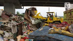 Petugas PPSU DKI Jakarta menggunakan alat berat mengangkut sampah di bawah Tol Becakayu, Cipinang Melayu, Jakarta Timur, Rabu (8/1/2020). Sampah sisa banjir tersebut selanjutnya diangkut ke TPA Bantar Gebang. (merdeka.com/Magang/Muhammad Fayyadh)