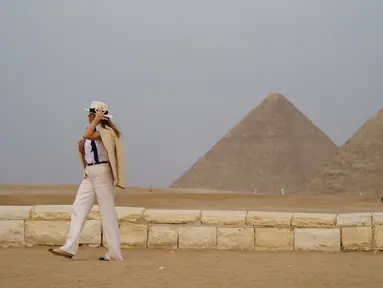 Ibu Negara AS Melania Trump memegang topinya saat berkunjung ke situs bersejarah Piramida Giza, Kairo, Mesir (6/10). Melania tampil mengenakan busana safari klasik saat mengunjungi destinasi terakhir selama seminggu di Afrika. (AP Photo/Carolyn Kaster)
