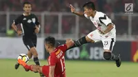 Pemain depan Madura United, Bayu Gatra melompat menghindari tekel bek Persija, Gunawan DC pada lanjutan Go-Jek Liga 1 Indonesia 2018 bersama Bukalapak di Stadion GBK Jakarta, Sabtu (12/5). Madura United unggul 2-0. (Liputan6.com/Helmi Fithriansyah)