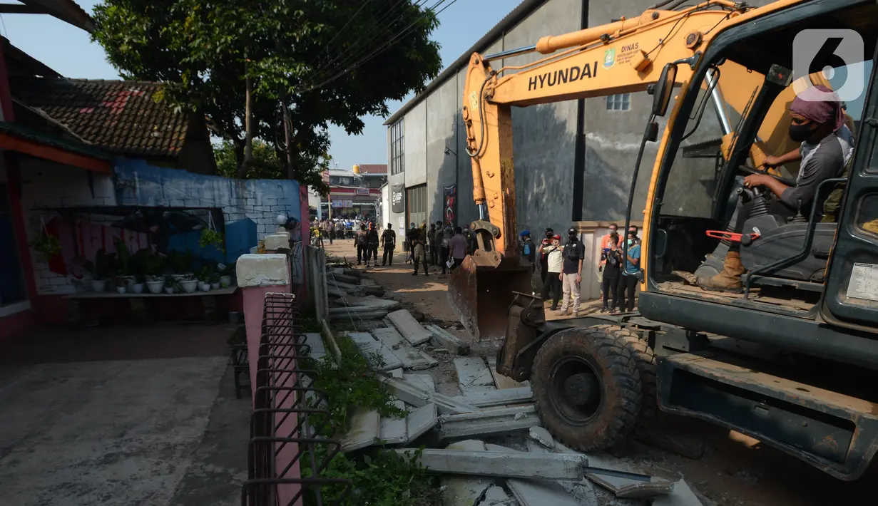 Pekerja menggunakan alat berat saat merobohkan pagar beton yang mengisolasi sejumlah warga di Jalan Akasia, Tajur Ciledug, Tangerang, Banten, Rabu ( 17/3/2021). Pagar beton yang sempat menutup akses jalan warga tersebut kini dibongkar. (merdeka.com/Imam Buhori)