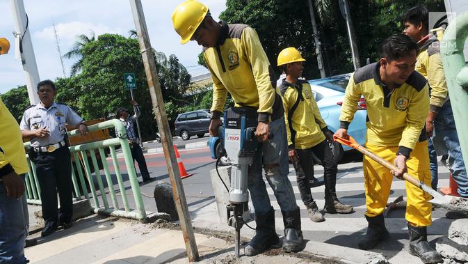 Aktivitas pekerja yang sedang membongkar pagar pembatas besi di kawasan Pinang Ranti, Jakarta, Senin (11/2). Zebra cross tersebut sempat menjadi perbincangan lantaran terhalang oleh pagar besi hijau setinggi 1 meter. (Liputan6.com/Herman Zakharia)