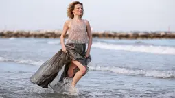 Sonia Bergamasco berlari sambil tersenyum saat bermain di pantai sebelum Festival film Venice ke-73 di Venice, Italia (30/8). Lahir di Milan Sonia Bergamasco memulai debutnya di film Miracoli pada tahun 1994. (REUTERS/Alessandro Bianchi)