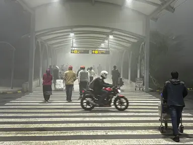 Para pelancong berjalan menuju terminal untuk melakukan penerbangan di tengah kabut pagi di Bandara Internasional Indira Gandhi, di New Delhi, India, Senin, 25 Desember 2023. (AP Photo/Manish Swarup)