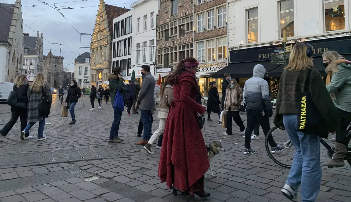 Orang-orang berjalan di kawasan shopping street di Ghent, Belgia, Rabu (22/12/2021). Mulai hari Minggu, pihak berwenang telah memutuskan menutup bioskop, teater dan ruang konser, sementara penggemar olahraga akan dilarang masuk stadion dan aula dalam ruangan. (AP Photo/Virginia Mayo)