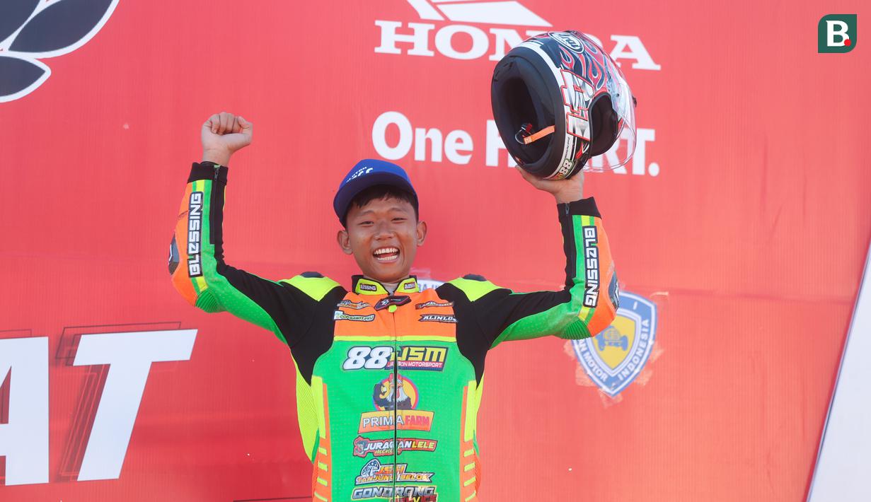 Pemabalap tim 88JSM, Fahri Irawan, melakukan selebrasi di atas podium setelah menjuarai kelas HDC 11 Honda Vario 160 cc standar lokal Sumut pada ajang Honda Dream Cup 2025 di Sirkuit Multifungsi Dispora Sumut Jl. Pancing Medan, Minggu (18/5/2025). (Bola.com/M Iqbal Ichsan)