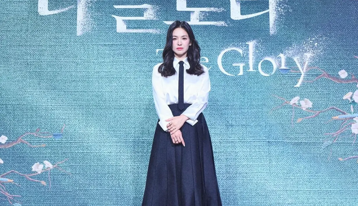 <p>Ia memadukan kemeja putih dengan dasi dan rok midi warna hitam. @netflixkr.</p>