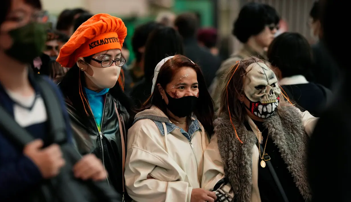 Orang-orang dengan kostum berjalan menyeberangi persimpangan jalan yang terkenal saat perayaan Halloween di distrik hiburan Shibuya, Tokyo, Jepang, 31 Oktober 2022. (AP Photo/Hiro Komae)