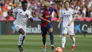 Penyerang Real Madrid, Vinicius Junior, berduel dengan winger Barcelona, Lamine Yamal, pada laga pekan ke-35 La Liga di&nbsp;Estadi Olimpic Lluis Companys, Minggu (11/5/2025) malam WIB. Dalam duel itu, El Real keok 3-4 dari El Barca. (AP Photo/Joan Monfort)