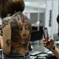 Seorang laki-laki mengambil gambar badan wanita yang dipenuhi tato pada saat acara International Malaysia Tattoo Expo di Kuala Lumpur, Malaysia.(AFP/Mohd Rasfan)