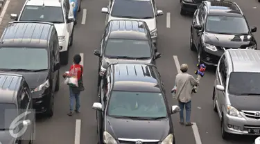 Pedagang asongan menjajakan dagangannya di tengah kemacetan kawasan Harmoni, Jakarta, Selasa (19/4). Kemacetan yang semakin parah di Ibukota menjadi keuntungan tersendiri bagi para pedagang asongan untuk mencari nafkah. (Liputan6.com/Immanuel Antonius)