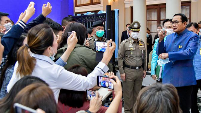 PM Thailand, Prayut Chan-O-Cha menyemprotkan pembersih tangan ke wartawan untuk menghindari pertanyaan perombakan kabinet selama konferensi pers di Bangkok, Selasa (9/3/2021). Sebelum menyemprot, Prayuth mengatakan kepada wartawan untuk mengurus urusan mereka sendiri. (HO/ROYAL THAI GOVERNMENT/AFP)