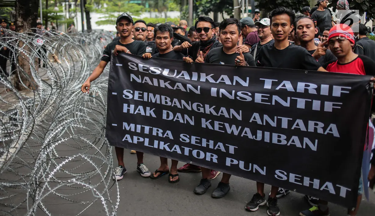 Pengemudi online membentangkan spanduk saat menggelar aksi di kantor pusat Grab, Jakarta, Senin (29/10). Mereka menuntut penentuan tarif dan skema yang manusiawi, serta monopoli dan diskriminasi order (order prioritas). (Liputan6.com/Faizal Fanani)