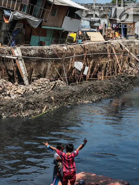 Anak-anak bermain dekat sejumlah rumah yang hampir ambruk akibat amblesnya tanah di bantaran Anak Kali Ciliwung di Jalan Lodan Raya, Pademangan, Jakarta, Senin (19/11). Sebanyak 21 warga terpaksa diungsikan sementara. (Liputan6.com/Faizal Fanani)