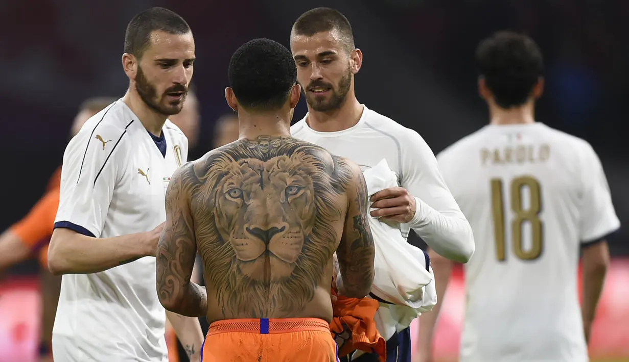 Penyerang Belanda, Memphis Depay, bertukar baju dengan gelandang Italia, Leonardo Spinazzola. Dalam pertandingan tersebut Italia berhasil menciptakan lima kesempatan, sedangkan Belanda memperoleh empat tendangan tepat sasaran. (AFP/John Thys)