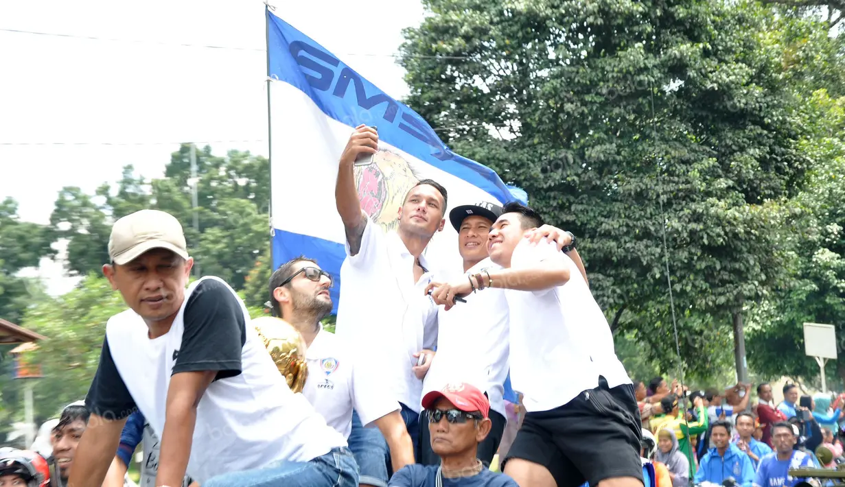 Pemain Arema Cronus berselfie ria saat pawai juara Torabika Bhayangkara Cup 2016 menuju Pendopo Kabupaten Malang, Selasa (5/4/2016). (Bola.com/Iwan Setiawan) 
