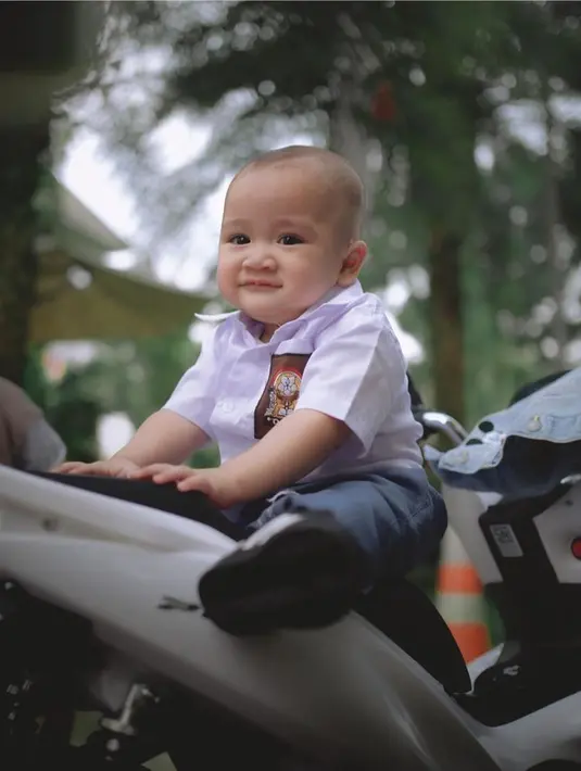 Nagita Slavina sangat senang mendandani Cipung dengan berbagai gaya. Seperti bergaya bak anak SMA. Gaya Cipung bak anak SMA ini terlihat menggemaskan terlebih ia juga berpose senyum di atas motor. (Liputan6.com/IG/raffinagita1717)