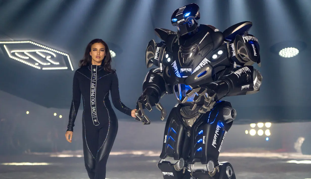 Model Irina Shayk melenggang ditemani robot sambil membawakan koleksi desainer Philipp Plein dalam New York Fashion Week 2018, Sabtu (10/2). Robot warna hitam yang bentuknya menyerupai Transformers itu lalu berjalan di sepanjang catwalk  (AP/Craig Ruttle)