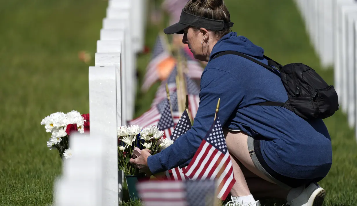 Seorang pengunjung meninggalkan karangan bunga di kuburan di Pemakaman Nasional Fort Logan, Sheridan, Colorado, Amerika Serikat, 30 Mei 2022. (AP Photo/David Zalubowski)