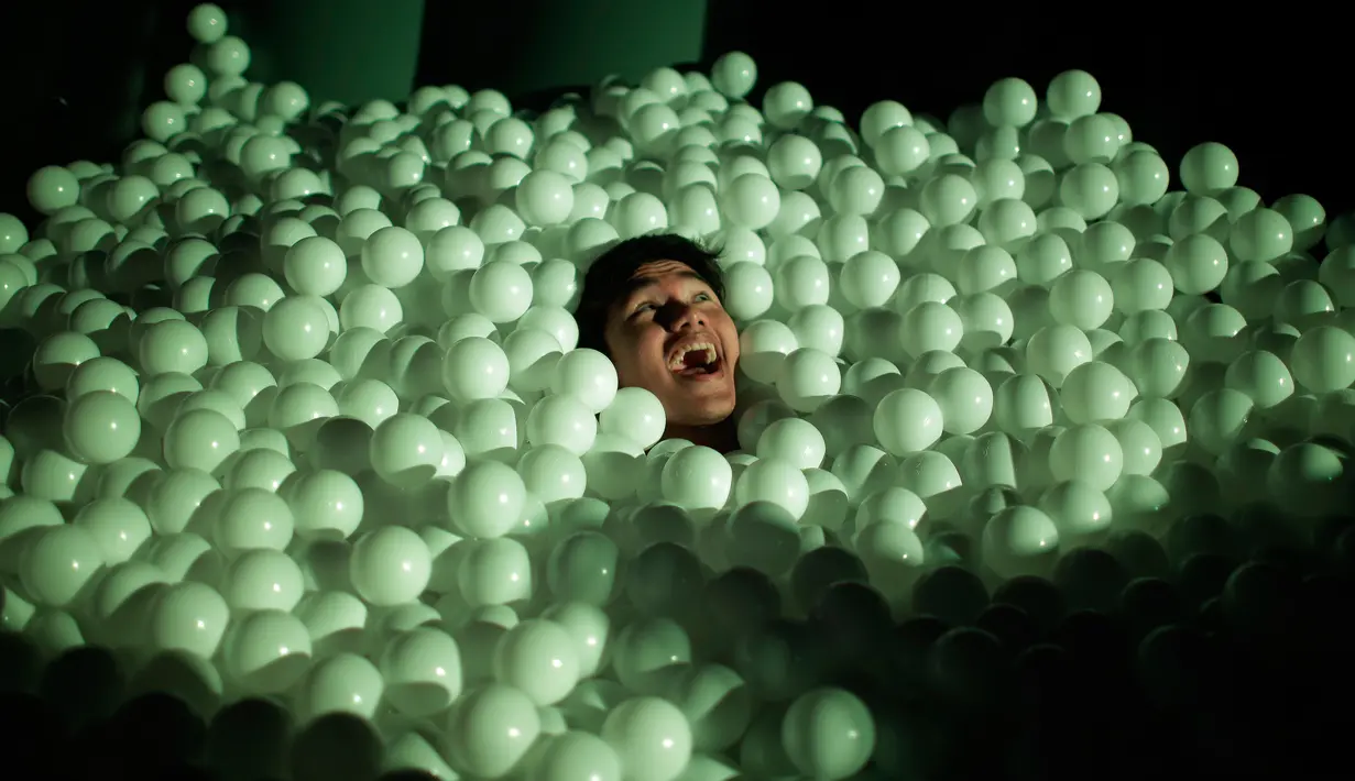 Seorang pengunjung berbaring di dalam ribuan bola plastik saat festival Light Marina Bay di Singapura (8/3). Pameran ini menampilkan karya kreatif berskala besar di dalam ruang kota. (AP Photo / Wong Maye-E)