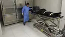 Ahli patologi membawa brankar jenazah pasien Covid-19 ke kamar mayat Rumah Sakit Lozenets di Sofia, Selasa (9/11/2021). Pemerintah Bulgaria melaporkan 334 kematian harian akibat COVID-19 pada Selasa, yang merupakan rekor tertinggi sejak awal pandemi. (Nikolay DOYCHINOV/AFP)