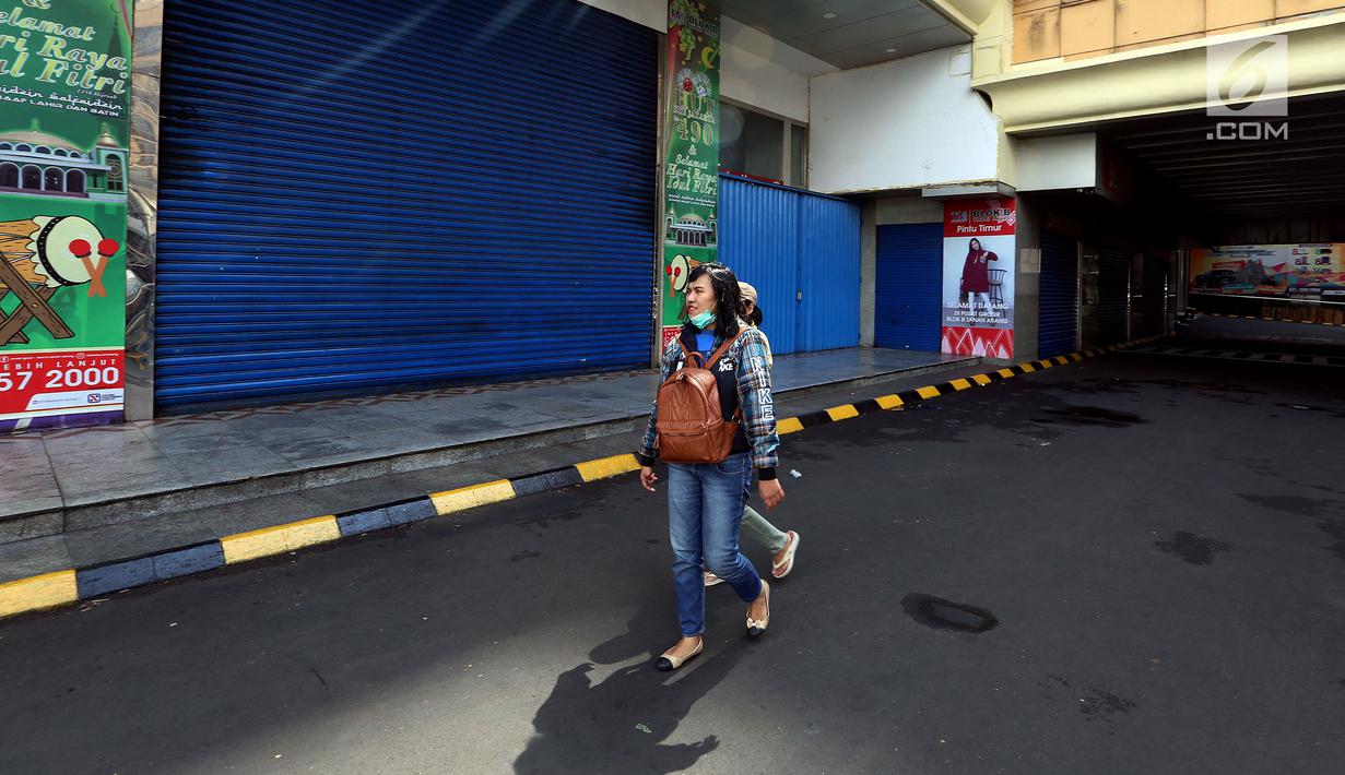 Warga melintasi sejumlah kios yang tutup di Blok B Pasar Tanah Abang, Jakarta, Selasa (27/6). Dalam rangka libur lebaran, Pasar Tanah Abang tutup mulai Minggu (25/7) hingga buka kembali pada tanggal 3 Juli 2017. (Liputan6.com/Johan Tallo)