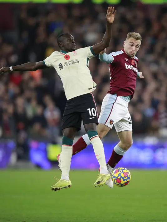 Penyerang Liverpool, Sadio Mane berebut bola dengan pemain West Ham United, Jarrod Bowen pada pertandingan lanjutan Liga Inggris di stadion London (8/11/2021). Liverpool yang kehilangan poin harus melorot ke posisi keempat dengan total 22 poin. (AP Photo/Ian Walton)