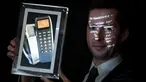 Petugas menyajikan layar yang menunjukkan telepon dengan SMS pertama di dunia sebelum dilelang dalam bentuk 'token digital yang tidak dapat disalin atau ditukar' (NFT) di rumah lelang Aguttes, Paris, Senin (20/12/2021). SMS itu diharapkan menerima tawaran sebesar USD 200.000. (ALAIN JOCARD/AFP)