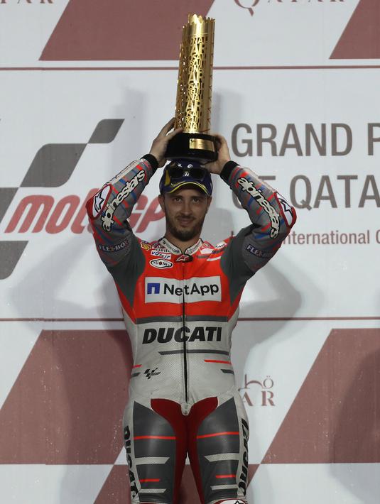 Pembalap Ducati Andrea Dovizioso berpose diatas podium sambil memegang pialanya usai memenangkan balapan di MotoGP Qatar 2018 di Sirkuit Internasional Losail (18/3). (AFP Photo/Karim Jaafar)