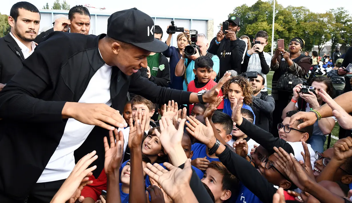 Bintang Prancis, Kylian Mbappe, menyapa anak-anak saat mengunjungi markas AS Bondy di Paris, Rabu (17/10). Kunjungan ke klub pertamanya ini dilakukan setelah dirinya meraih gelar Piala Dunia 2018. (AFP/Franck Fife)