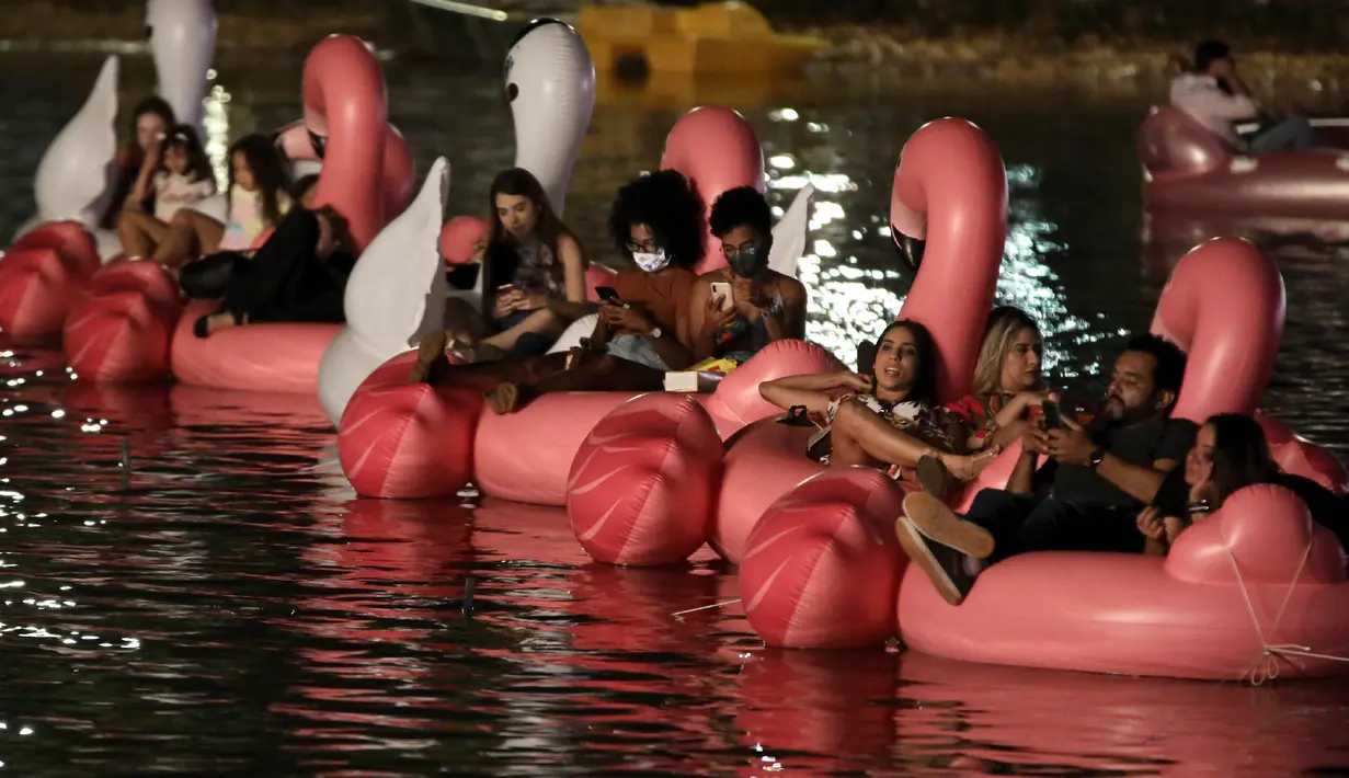 Orang-orang bersantai di atas balon flamingo saat mereka menonton film selama Festival Terapung pertama di Danau Sarah Kubstichek Brasilia, Brasil (30/9/2020). Brasil mengadakan festival pertama yang mengusung tema terapung. (AP Photo/Eraldo Peres)