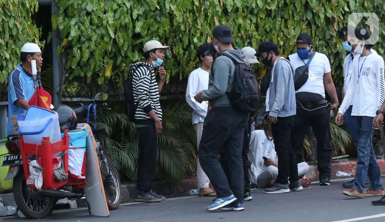 Polisi berpakaian kaus putih memeriksa sekelompok anak muda yang dicurigai terlibat kericuhan di kawasan Tugu Tani, Jakarta, Selasa (13/10/2020). Sejumlah pemuda diamankan polisi karena dicurigai terlibat kericuhan di kawasan Tugu Tani. (Liputan6.com/Helmi Fithriansyah)