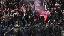Polisi anti huru hara Prancis tiba ketika para penonton menyalakan suar pada pertandingan 64 besar Piala Prancis antara Paris FC dan Olympique Lyon di stadion Charlety, Jumat (17/12/2021). Pendukung saling bertarung dan beberapa dari mereka turun ke lapangan dan melemparkan suar. (Bertrand GUAY/AFP)