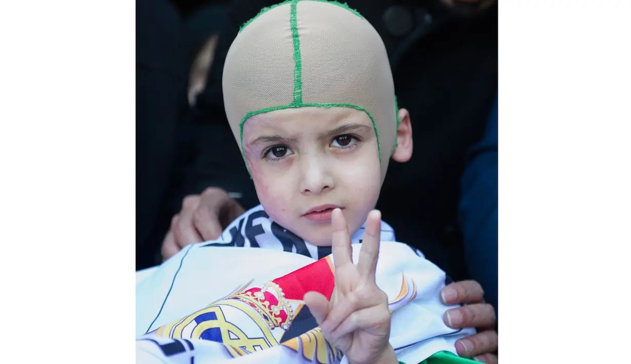 Ahmed Dawabsha adalah bocah berusa 5 tahun yang selamat dari bom di Palestina mengenakan bendera Real Madrid saat tiba di Bandara Adolfo Suarez, Madrid, Rabu (16/3/2016).  (AFP/Curto De La Torre)