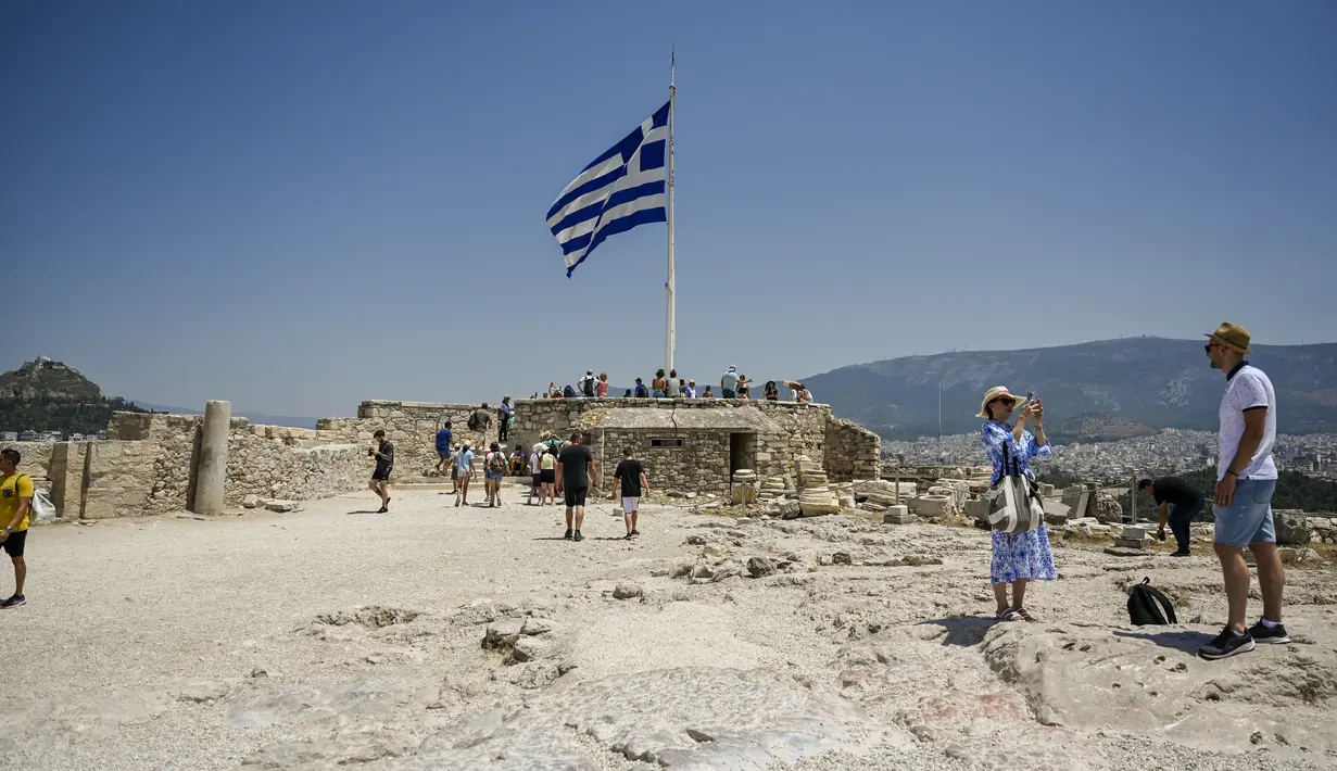 Turis mengambil foto saat mengunjungi Acropolis di Athena, Yunani, Minggu (24/7/2022). Negara ini berada dalam cengkeraman gelombang panas yang dimulai pada 23 Juli dan akan berlangsung beberapa hari. Suhu diperkirakan akan mencapai 42 derajat Celcius (107 derajat Fahrenheit) di beberapa daerah.
(Louisa GOULIAMAKI / AFP)