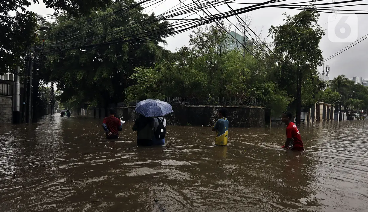 Warga melintasi banjir di Jalan Hang Lekir, Kebayoran Lama, Jakarta Selatan, Rabu (1/1/2020). Banjir tersebut disebabkan karena tingginya intensitas hujan yang mengguyur sejak Selasa (31/12/2019). (Liputan6.com/Johan Tallo)