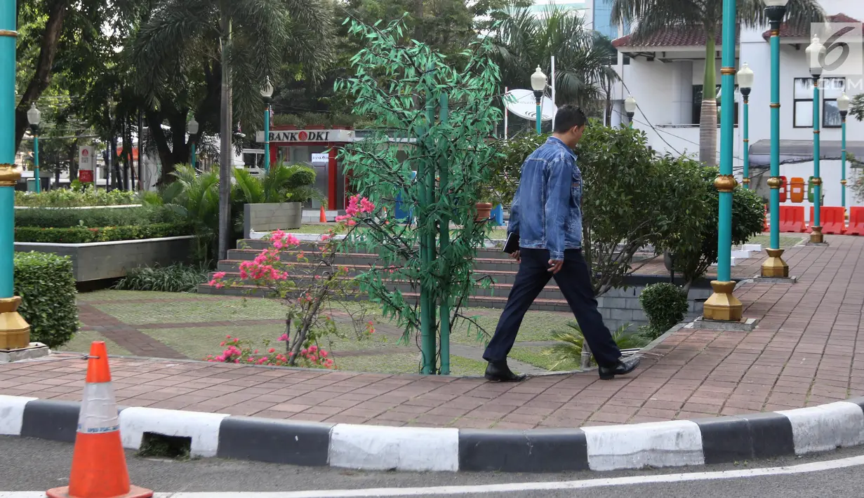 Seorang pegawai melintas di samping pohon imitasi yang terpasang di halaman Balai Kota DKI Jakarta, Senin (4/6). (Liputan6.com/Arya Manggala)