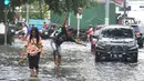 Warga dan kendaraan melintasi banjir di kawasan Green Garden, Jakarta Barat, Selasa (5/3). Sejumlah ruas jalan di Jakarta Barat tergenang air akibat luapan Kali Angke dan drainase yang buruk serta pasang air laut. (merdeka.com/Arie Basuki)
